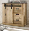 A wooden sideboard with a sliding barn door and drawers, set against a white brick wall. Produktbild-Vorschau