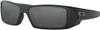 A pair of black Oakley Gascan sunglasses with gray lenses, shown from a front-side angle against a white background. Náhled obrázku produktu