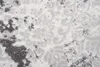 A close-up view of a textured carpet with a modern abstract pattern in beige and gray tones. Produktbild-Vorschau