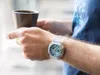 A person holding a cup of coffee while wearing a watch. Anteprima dell’immagine prodotto