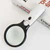 A white and black LED-illuminated magnifying glass rests on top of two books. Náhled obrázku produktu