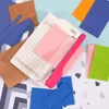 A paper trimmer and various colored paper sheets are arranged on a patterned background. Anteprima dell’immagine prodotto