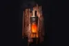 A perfume bottle is placed on a piece of rough wood against a dark background. Anteprima dell’immagine prodotto