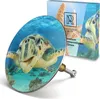 A close-up of a decorative bath plug with a turtle motif, shown alongside its packaging. Produktbild-Vorschau