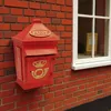 A red retro post box mounted on a brick wall next to a window. Produktbild-Vorschau