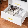A close-up view of an open drawer in a white cabinet, showing books and headphones inside. Produktbild-Vorschau