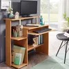 A computer desk with a monitor, keyboard, and various office supplies, placed in a room with a window and a chair. Anteprima dell’immagine prodotto