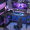 A gaming setup with an L-shaped desk, computer, monitors, and chair, illuminated by LED lights. Anteprima dell’immagine prodotto