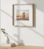 A framed family photo on a wall above a vase and books. Produktbild-Vorschau