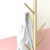 A gold coat rack with a blue and white checkered shirt hanging on it, against a white and pink background. Produktbild-Vorschau
