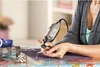 A person is using a Dremel tool to engrave or polish a piece of jewelry. Produktbild-Vorschau