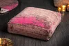 A floor cushion with an abstract pattern is placed on a dark wooden floor, with candles and a woven basket in the background. Produktbild-Vorschau