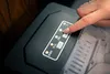 A person's hand is pressing a button on the control panel of an ice maker. Podgląd zdjęcia produktu