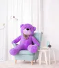 A large purple teddy bear sits in a light blue armchair in a well-lit room with sheer white curtains in the background. Voir les images du produit