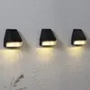 Three black solar wall lights mounted on a textured light gray wall. Produktbild-Vorschau