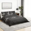 A bedroom scene with a bed dressed in black bedding with white text. Voir les images du produit