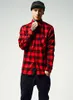A man wearing a red and black checkered flannel shirt and black pants, posing against a white background. Produktbild-Vorschau