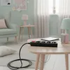 A power strip with multiple outlets is placed on a wooden coffee table in a living room setting. Náhled obrázku produktu