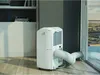 A portable air conditioner is shown in a room, connected to a window. Voir les images du produit