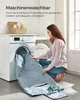 A woman is putting a blanket into a washing machine. Produktbild-Vorschau