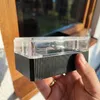 A hand holding a small black and clear plastic box with ribbed sides, in front of a window. Náhľad obrázku produktu