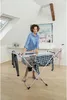 A woman is hanging laundry on a drying rack in a room with a sloped ceiling. Anteprima dell’immagine prodotto