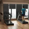 Two treadmills in a gym with a man running on one of them. Produktbild-Vorschau