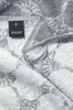 A close-up view of a grey towel with a black brand tag. Podgląd zdjęcia produktu