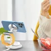 A person is eating watermelon next to a charging station with a phone, watch, and earbuds. Produktbild-Vorschau