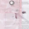 A close-up view of a pink sheer curtain with a floral pattern, showing a grommet and text printed on a page behind it. A small cactus plant in a white pot is also visible. Produktbild-Vorschau