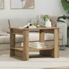 A wooden side table with two shelves is placed in a living room setting next to a sofa. Decorative items like books, a vase with water and lime, and a plant are on the table. Podgląd zdjęcia produktu
