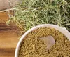 A bucket of animal feed pellets and a pile of hay on a wooden surface. Produktbild-Vorschau