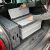 A person is placing a lid on a foldable storage box in the trunk of a car. Produktbild-Vorschau