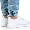 A person wearing white Puma sneakers and acid-wash jeans. Anteprima dell’immagine prodotto