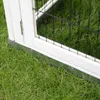 Close-up of the bottom corner of a white wooden animal hutch with a metal base, sitting on green grass. Voir les images du produit