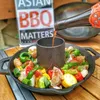 A cast iron chicken roaster with vegetables and sauce being poured into it. Anteprima dell’immagine prodotto