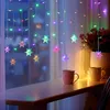 A string of colorful snowflake-shaped LED lights hangs in front of a window, with two mugs on a wooden shelf below. Náhled obrázku produktu