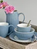 A set of blue ceramic tableware with pink flowers on a tray. Produktbild-Vorschau
