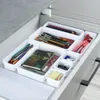 An open drawer with white modular organizers filled with office and art supplies. Náhľad obrázku produktu