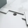 A close-up view of a white shower tray with a drain. Produktbild-Vorschau