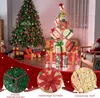 A festive indoor scene with a decorated Christmas tree and a stack of illuminated gift boxes. Produktbild-Vorschau