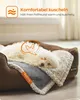 A small white dog is sleeping on a brown dog bed with a blanket. Produktbild-Vorschau