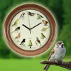 A clock with bird illustrations and a real bird perched on a branch in the foreground. Náhled obrázku produktu
