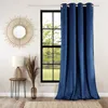 A blue velvet curtain hangs next to a window with a view of greenery. A small side table with a lamp and dried flowers is placed nearby. Anteprima dell’immagine prodotto