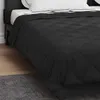 A close-up view of a black quilted comforter on a bed. Produktbild-Vorschau