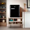 A black retro mini-fridge sits on a shelf unit next to a bookshelf. Produktbild-Vorschau