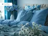 A neatly made bed with blue bedding and pillows, decorated with white flowers. Produktbild-Vorschau