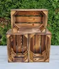 Three wooden crates are stacked on a light-colored surface in front of a green hedge. Produktbild-Vorschau