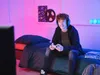 A young person is playing a video game in a room with colorful lighting. Voir les images du produit