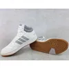 A pair of white Adidas Hoops 3.0 Mid sneakers with gray accents and a brown sole, displayed on a light gray textured background. Produktbild-Vorschau